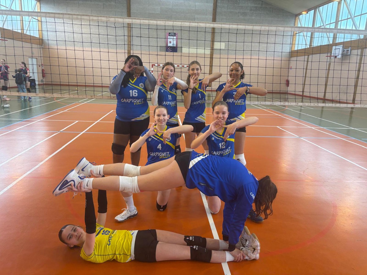 Équipe de jeunes joueuses en maillots bleu et jaune, faisant des gestes de la main, dans un gymnase